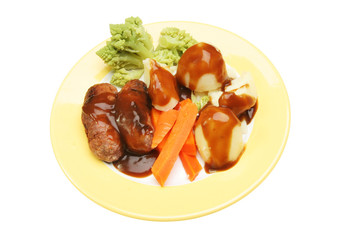 Sausages gravy and vegetables on plate