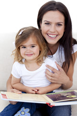 Smiling mother and daughter reading a book