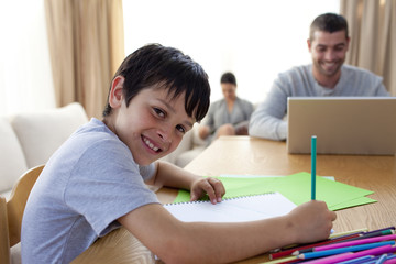Naklejka premium Boy painting and father using a laptop and mother reading