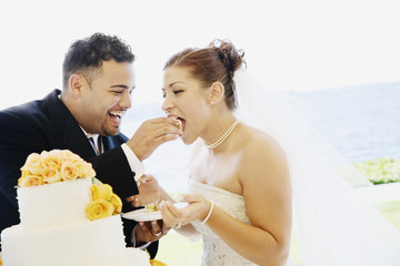 Multi-ethnic bride and groom eating cake