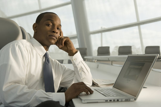 African businessman working on laptop and looking serious