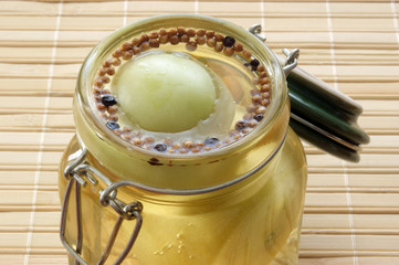 green tomato in a jar with vinegar and spice