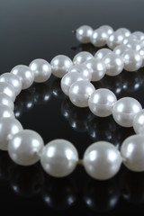 pearl necklace on a dark background with reflection