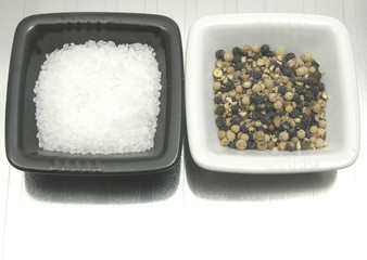 Porzellanschalen mit Salz und Pfeffer auf spiegelnder Unterlage