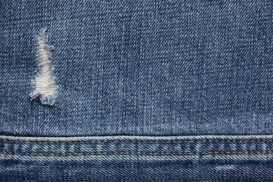 Blue denim jeans textured background with a hole