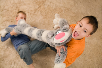 Naklejka premium Two kids with a toy cat on the floor