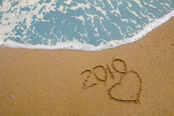 Year 2010 written on the sand