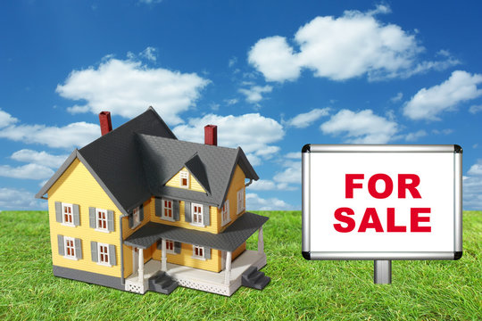 Model house on green grass with for sale sign