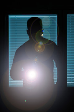 Silhouette of a man pointing with flashlight