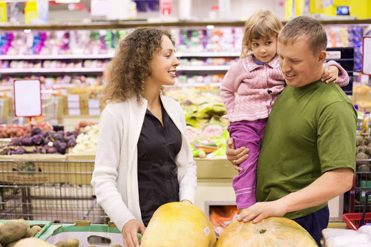 family with little girl  buy pumpkin in supermarket