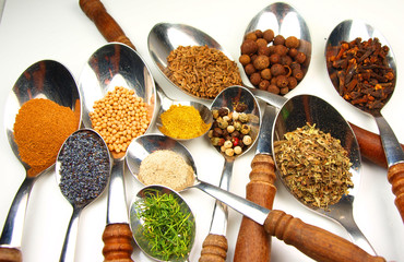 Collection of spices on wooden spoon isolated on white