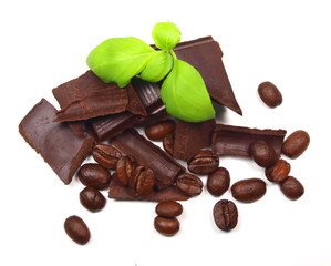 Chocolate pieces and slices with coffee beans and basil leaves