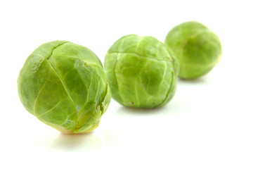Three Brussels sprouts in a row over white background