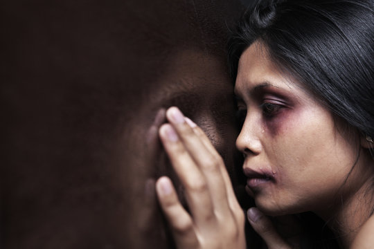 Injured woman leaning sadly on wooden wall