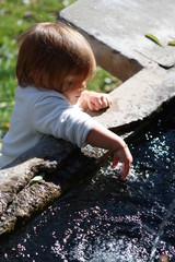 bébé fille de 15 mois découvrant l'eau d'une fontaine