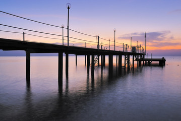 Fototapeta na wymiar Pier silhouette over sunrise glow