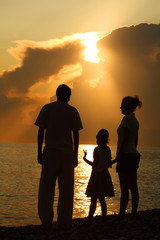 Family of three person on sunset background