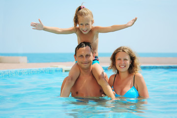 Fototapeta na wymiar smiling family in pool. Daughter sits on fathers shoulder