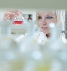 Closeup of a female researcher holding up a test tube and a reto
