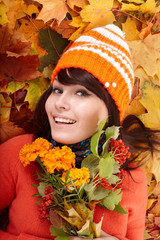 Girl in autumn orange hat on leaf group with flower.Outdoor.