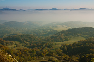 green valley with mountains in fog