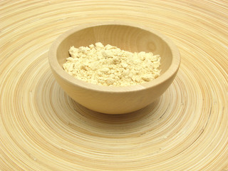 Holzschale mit Sojamehl auf Bambusteller