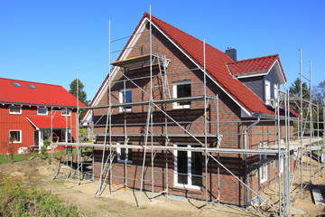 Neubau Einfamilienhaus Baugerüst Rohbau blauer Himmel