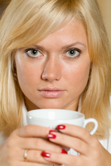 A close-up portpait of a blond with a cup