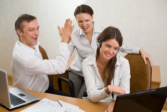 Group Of Young Employees With Laptops And  Clap Gesture