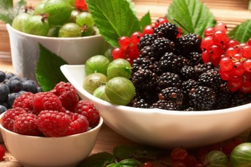 Berries in plates, on a table, among green leaves