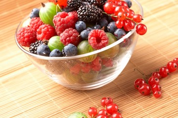 Fruit mix in the glass container, on a table from straw