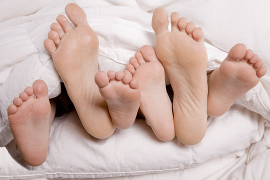 Woman and kids feet in bed