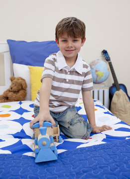 Little boy playing with a train in his bedroom