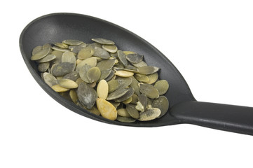 pumpkin seeds on plastic spoon on white background
