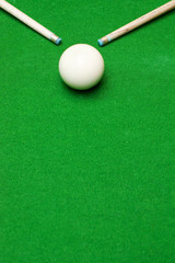 Ends of two pool cue sticks pointing at white ball on baize