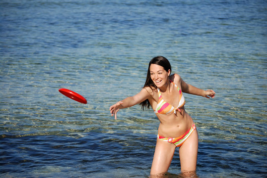 Woman throwing frisby at the beach