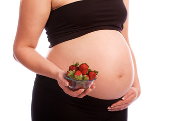 Pregnant Caucasian woman eating strawberries