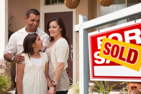 Hispanic Family in Front of Their New Home with Sold Sign