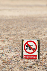 humorous no swimming sign on an empty beach