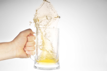 Hand holding mug with splashing beer