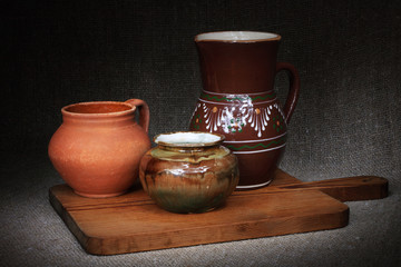 Ceramic pots on wooden cutting board, on sackcloth