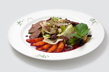 Salad from duck meat, oranges, leaves of salad and nuts and sauc