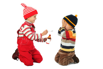 Little boy and smiling girl with spoon and bottle of medicine