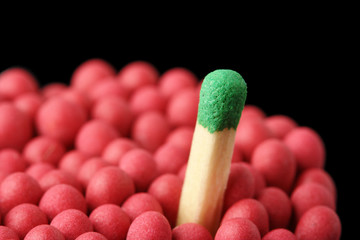 Single green matchstick among red ones, out of the crowd concept