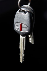 Auto keys and alarm trinket on black background.