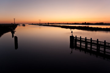 Fototapeta na wymiar Beautiful sunrise above a dutch river while a ship is approachin