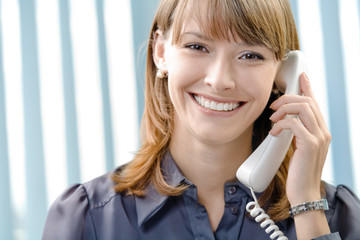 Portrait of happy businesswoman with phone at office