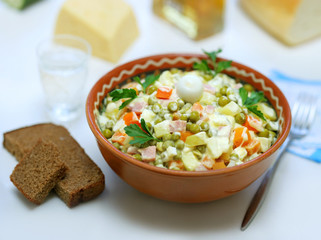 Homemade variant of Russian Salad and pieces of bread near