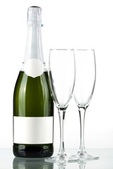 Bottle of champagne with blank label and with two empty glasses