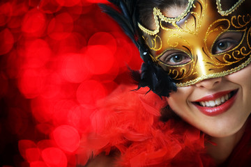 Beautiful young woman in carnival mask over red background